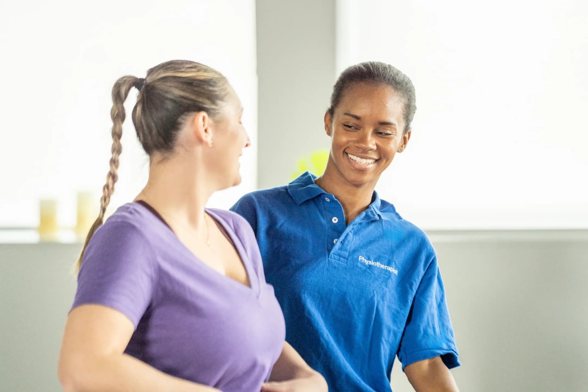 Physiotherapeutin begleitet eine Klientin bei einer sanften Bewegungsuebung