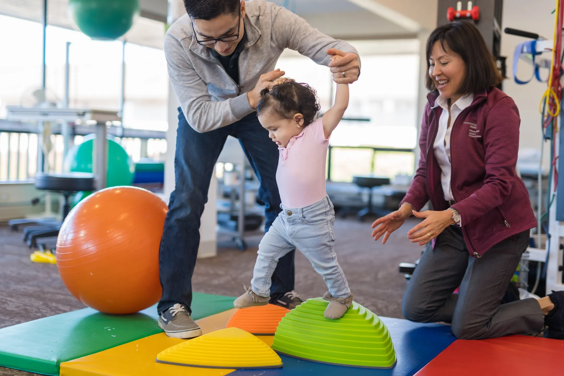 Ergotherapeutische Balanceuebung fuer ein Kind mit Unterstuetzung des Vaters